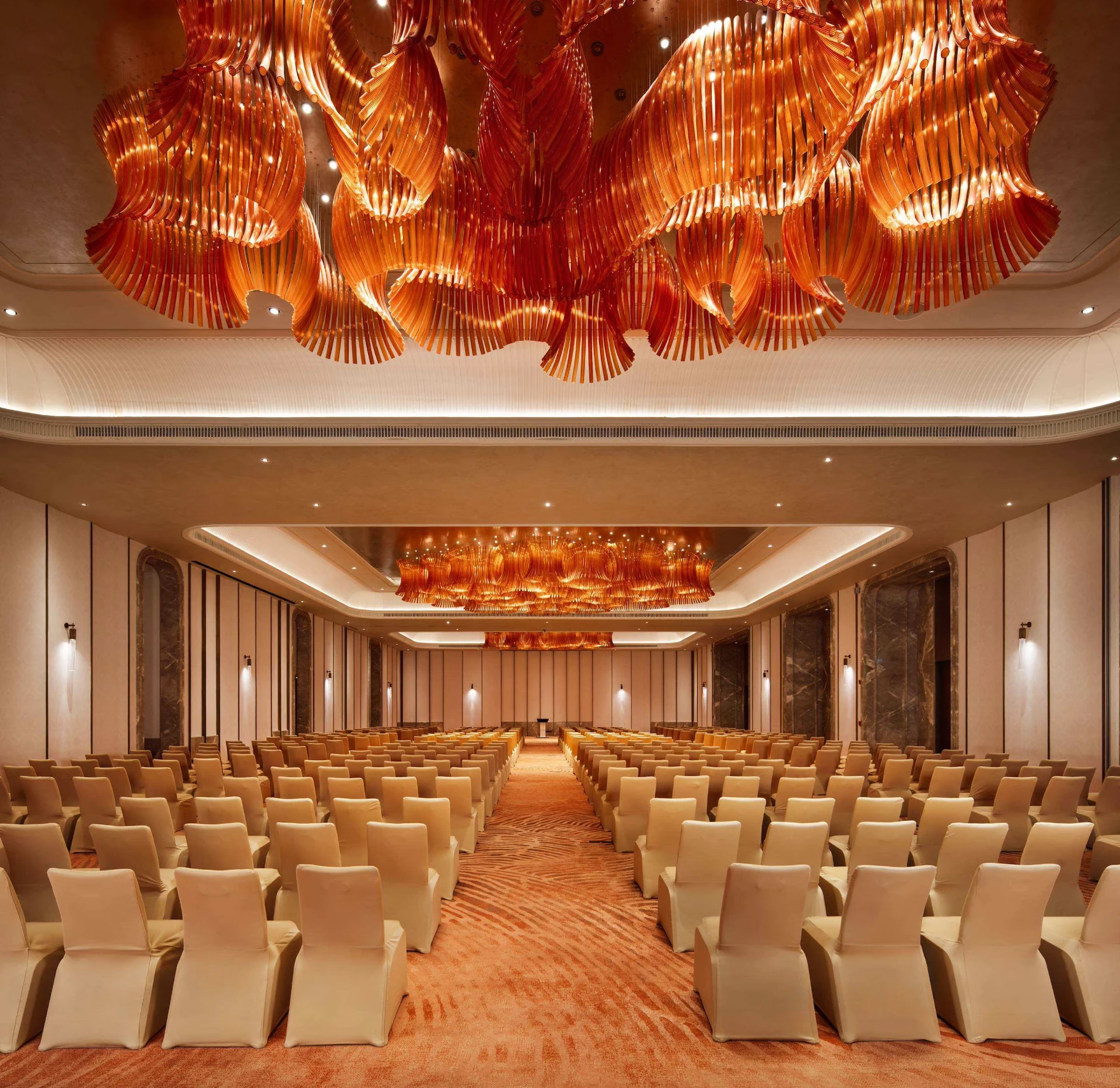 Conference ballroom with rows of chairs and sculptural amber chandeliers